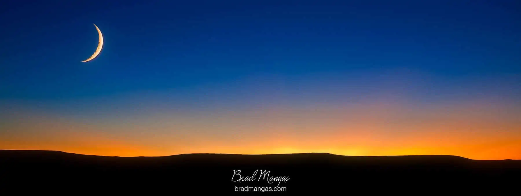 Cresent moon over the setting sun in the Kansas flint hills
